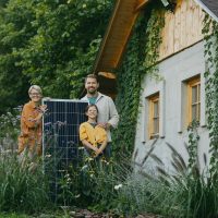 Family in garden holding solar panel. Solar energy and sustainable lifestyle of young family