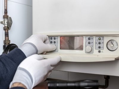 Technician servicing heating boiler in a house